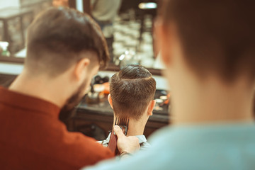 Barbershop. Close-up of man haircut, master does the hair styling in barber shop. Toned vintage photos.