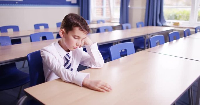 4k, Bored young student sitting alone in an empty class room during detention.