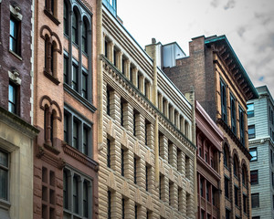 Fototapeta na wymiar Row of vintage New York City apartment buildings in a variety of brick and brownstone facades