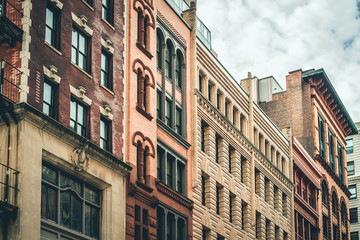 Row of vintage New York City apartment buildings in a variety of brick and brownstone facades