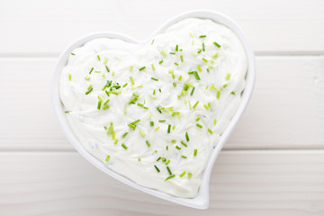 Bowl of cream cheese with green onions, dip sauce on wooden table.