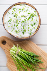 Bowl of cream cheese with green onions, dip sauce on wooden table.