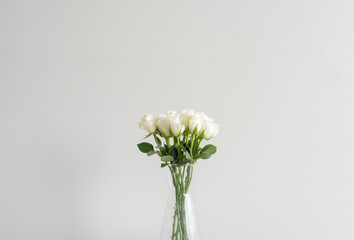 Cropped view of roses in glass vase against beige wall