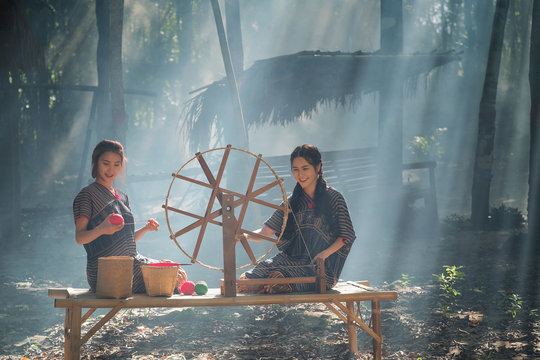 Two Beautiful Thai Women Smile In Karen Suit Spinning Thread On A Bamboo Mat In A Forest Nature Local Village Thailand