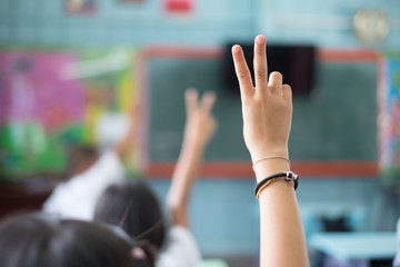 Student hands up answer a question in class at the elementary school. Education concept.