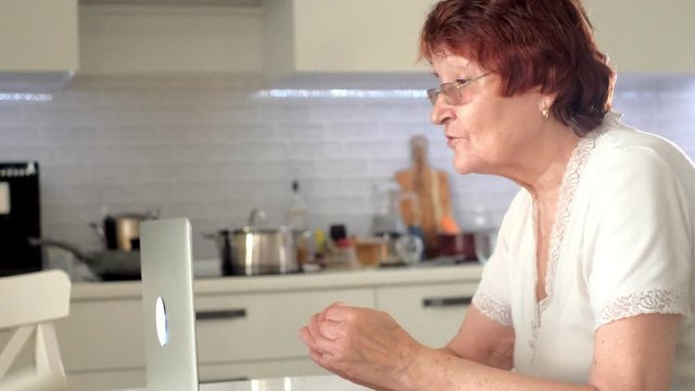 old woman talk with her granddaughter on skype using a laptop
