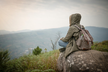 backpacker sitting on the rock with beautiful nature background
