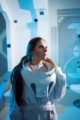 Portrait of a woman astronaut in a space suit, dreamy look up. Futuristic astronaut on Board the spacecraft. © Ulia Koltyrina