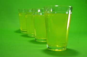 Vasos de licor de absenta transparentes en un fondeo de color verde