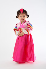 Smile Korean little girl wearing a Traditional Hanbok dress in white background. The characters on the dress means happiness and healthy.