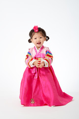 Smile Korean little girl wearing a Traditional Hanbok dress in white background. The characters on the dress means happiness and healthy.
