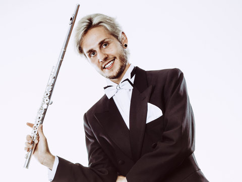 Male flutist wearing tailcoat holds flute