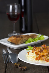 Spaghetti prawn and salmon steak on white dish and wine on wooden table with dark tone.