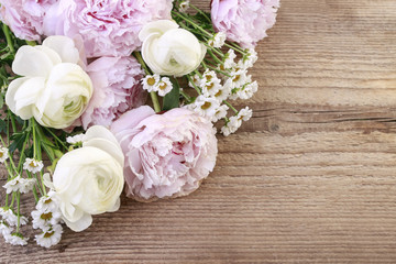 Pink peonies, white ranunculus flower and matricaria tanacetum on wood