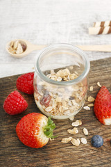 Jar of muesli and fresh strawberries around.