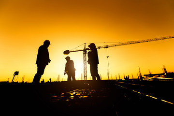 Fototapeta na wymiar silhouette group of worker and civil engineer in safety uniform install reinforced steel column in construction site during sunset time industrial concept