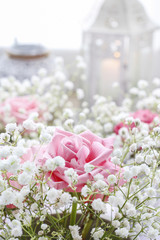 Floral arrangement with pink roses, gypsophila paniculata and candles.