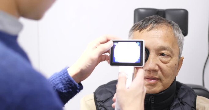 Asian old man checking on eye