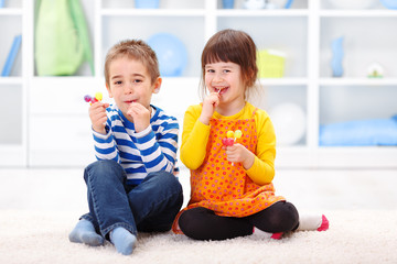 Little boy and girl eating lollipop