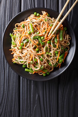 Japanese soba salad with vegetables and sesame close-up on the table. Vertical top view