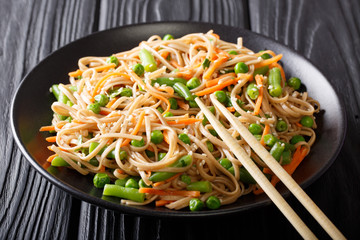 Japanese soba salad with vegetables and sesame close-up on a plate on the table. horizontal