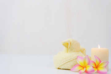 spa wellness set.beauty and fashion set on the white table.spa towel with candle and plumeria, tree on the white table.