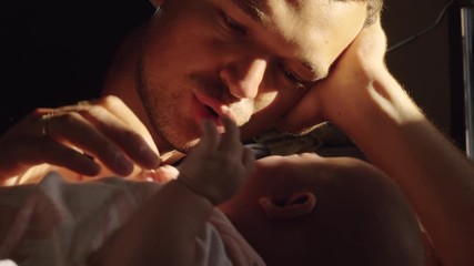 Happy father lying with baby daughter on bed but child is crying