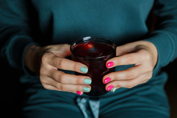 Obraz premium A horizontal image of woman's hands with bright pink and mint colour nails, holding a cocktail glass with an alcoholic drink. Selective focus.