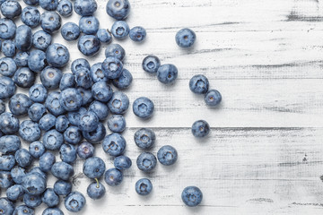 American blueberries scattered over white wooden background