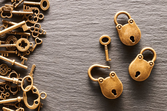 Various metal keys and locks on slate background