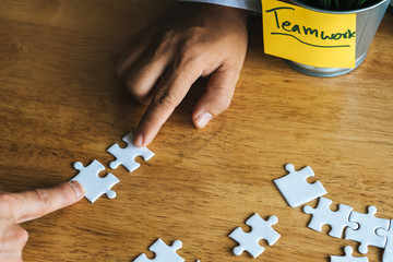 Teamwork, partners, connection concept. Hands of two businessmen merging jigsaw puzzle on the...