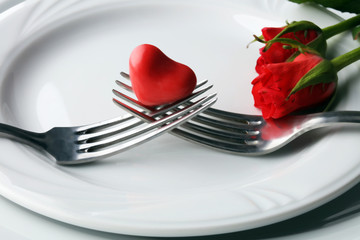 Festive table setting for Valentine's Day with fork, knife and rose