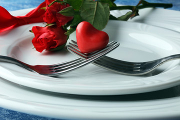 Festive table setting for Valentine's Day with fork, knife and rose