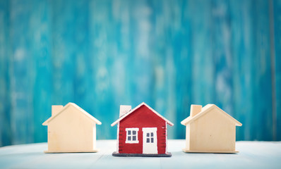 Red house model on blue wooden background. Property concept.