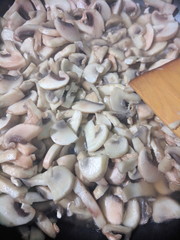 Sliced mushrooms are fried in a frying pan, mushrooms in a frying pan, mushrooms are prepared in the home kitchen, retro style, American cuisine, vegetarian food