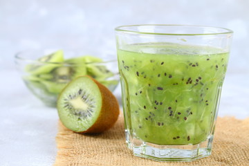 Sliced kiwi and smoothie slices in a glass on a gray table. Healthy food.