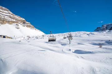 Fototapeta na wymiar Sunny day in the Alps - ski tracks, ski lifts and snowy mountains