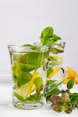 Two glass cups fresh mint tea with lemon and honey on white background.