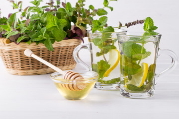 Basket with fresh green mint and two glass cups with fresh mint tea on white  background.