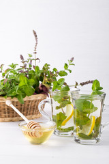 Basket with fresh green mint and two glass cups with fresh mint tea on white  background.
