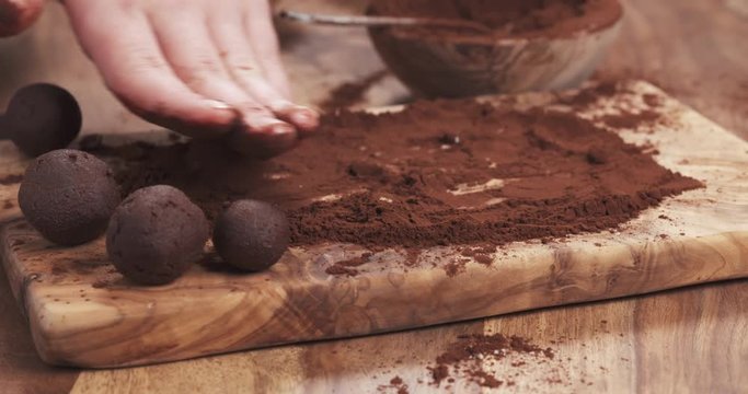 Slow motion handheld shot put truffles in cocoa powder on board