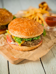 Burger with beef, salad, sauce and tomato on wooden table. American fact food