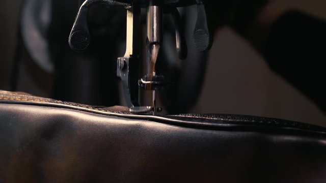 The tailor makes a handmade leather bag in the atelier
