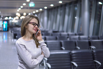 Young, beautiful girl talking on the phone in an empty airport terminal