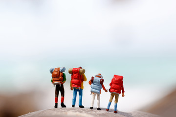 Miniature people: backpacker celebrating success standing on top at the peak of a mountain, Concept of the path to purpose and success.