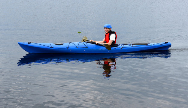 Happy young man kayaking on big lake in summer
