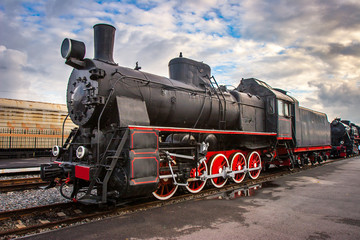 Fototapeta na wymiar Steam locomotive with red wheels. Retro locomotive on rails. Black locomotive.