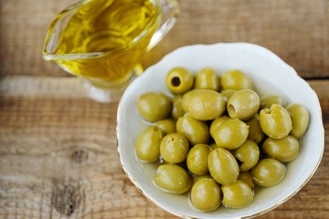 Delicious green olives and oil on the table 