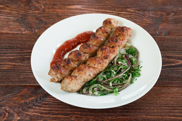 Portion luleh kebab on a plate. Appetizing dish on the wooden brown table.