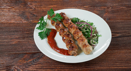 Portion luleh kebab on a plate. Appetizing dish on the wooden brown table.